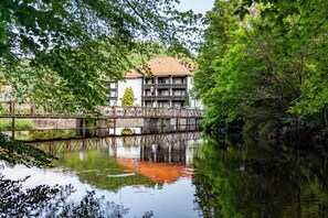 A building with a traditional architectural style, a bridge, and a calm water body reflecting the structure. - Mühl Vital Resort (Bad Lauterberg)
