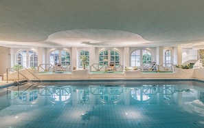 An indoor swimming pool with clear blue tiles, arched windows, and a white ceiling. - Mühl Vital Resort (Bad Lauterberg)