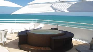 A hot tub on a deck with a view of the ocean.