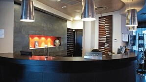 A reception desk with a 'RECEPTION' sign, a modern light fixture, and a wall with a decorative panel.
