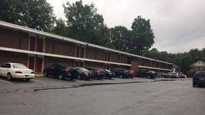 A parking lot with several cars parked in front of a motel with multiple rooms. - The Autumn Inn (Bennington)