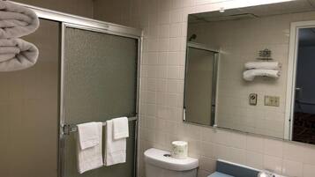 Une salle de bain avec une douche à parois de verre, des toilettes, un lavabo et un miroir.