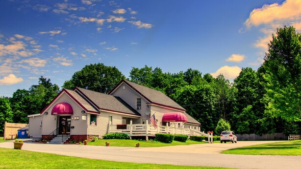 A two-story building with a red roof and a white fence. - The Autumn Inn (Bennington)