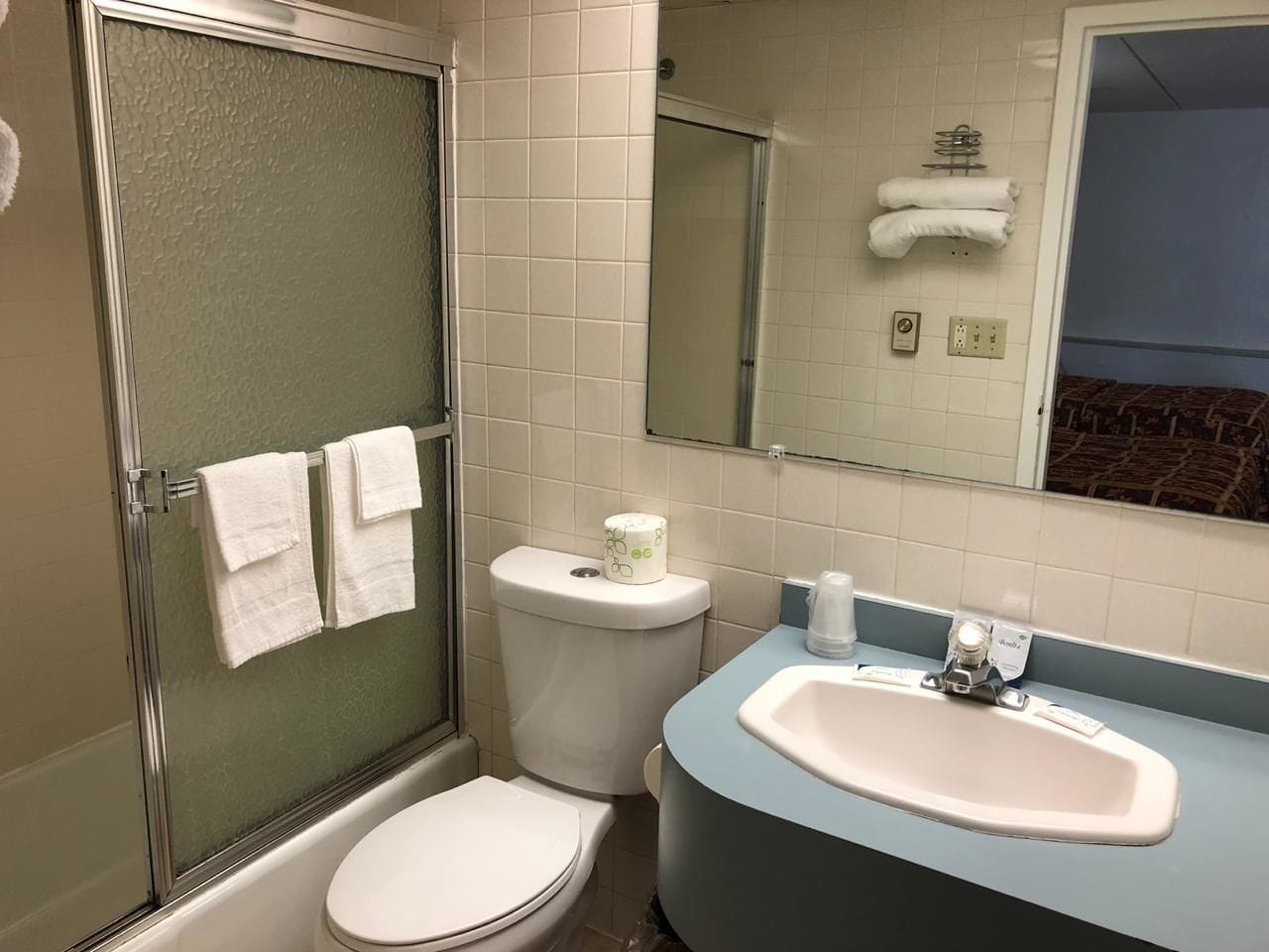 Un bagno con doccia vetrata, un WC bianco e un lavandino con piano blu.