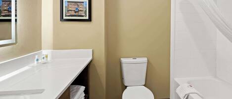 A bathroom with a white bathtub, toilet, and sink. There are framed pictures on the wall and a towel rack.