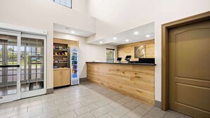 A reception area with a wooden counter, a vending machine, and a glass door leading outside. - Comfort Inn & Suites High Point - Archdale (High Point)
