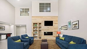 A modern living room with two blue sofas, a coffee table, and a fireplace. - Comfort Inn & Suites High Point - Archdale (High Point)
