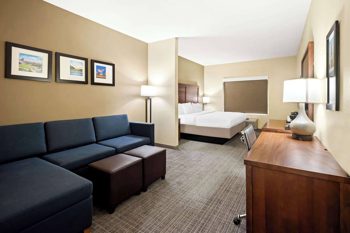 Une chambre d’hôtel avec un canapé, un lit, un bureau et des tableaux encadrés au mur.