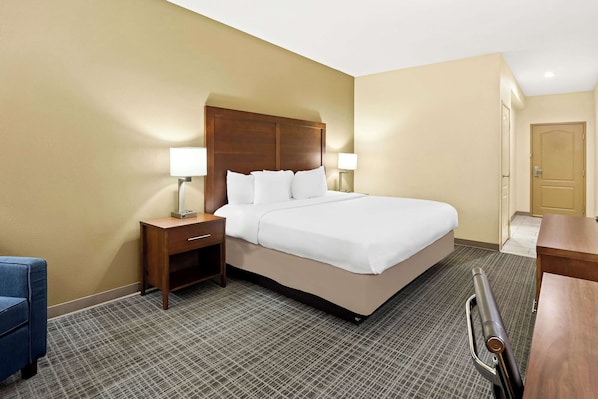 A hotel room with a large bed, two bedside tables with lamps, a desk, and a chair.