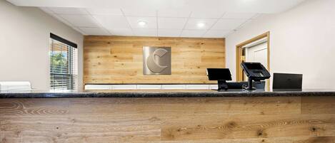 A reception area with a wooden floor, a reception desk with a computer and a phone, and a large wall-mounted logo.