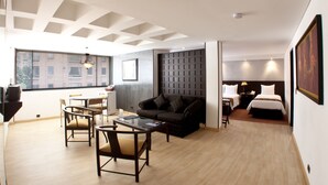 A modern hotel room with a dining area, a sofa, a bed, and a desk. - Hotel Centro Internacional (Bogotá)