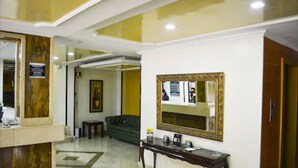 A reception area with a reception desk, a green sofa, a console table with a mirror, and a framed picture on the wall. - Hotel Centro Internacional (Bogotá)