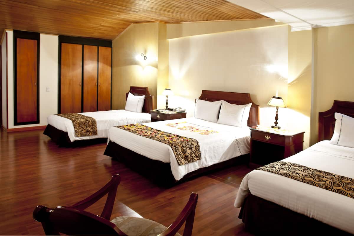 A hotel room with two beds, wooden flooring, and a wardrobe.