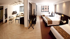 A hotel room with a bed, a desk, a chair, a TV, and a window with blinds. - Hotel Centro Internacional (Bogotá)