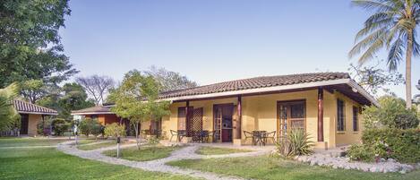 A two-story building with a tiled roof, a covered patio with outdoor furniture, and a well-maintained garden with a gravel path.