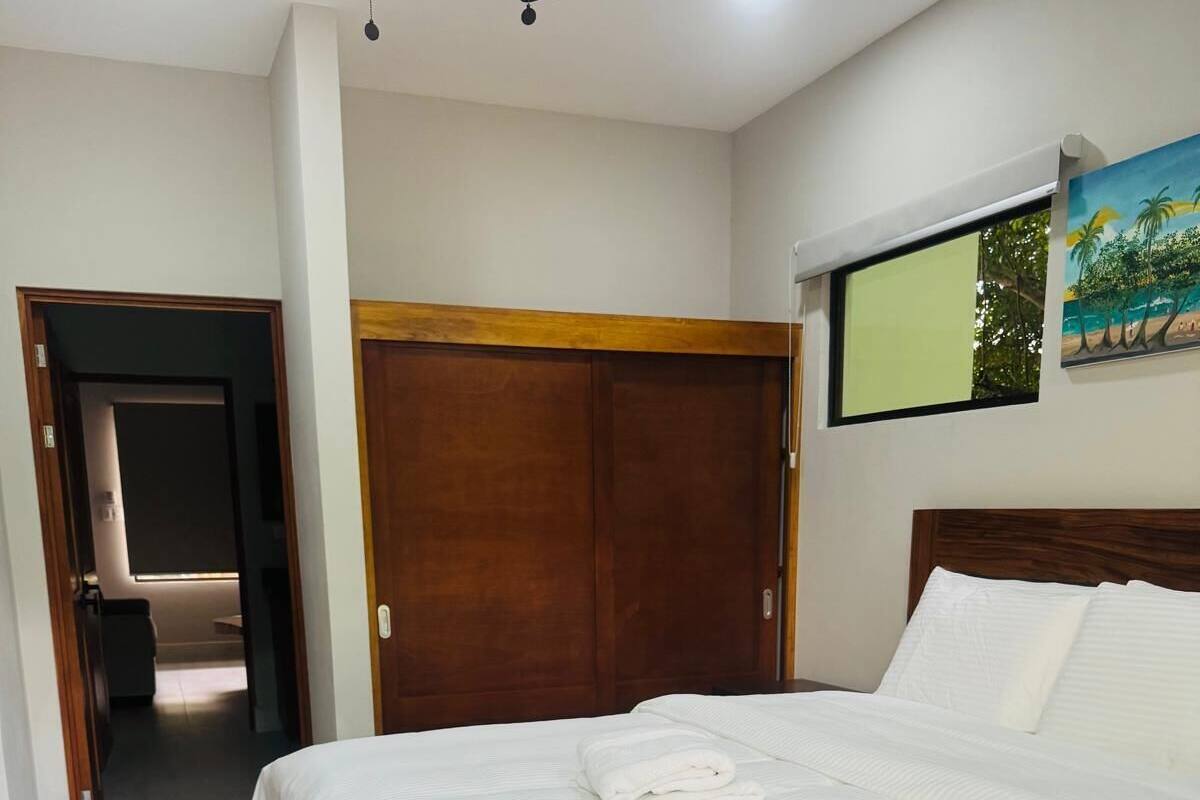 A bedroom with a bed, wooden wardrobe, and a ceiling fan.