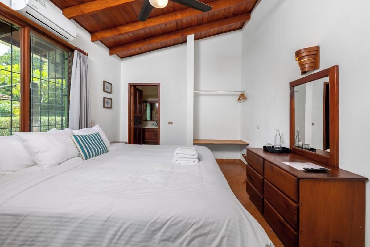 A bedroom with a large bed, wooden headboard, a dresser, and a mirror.