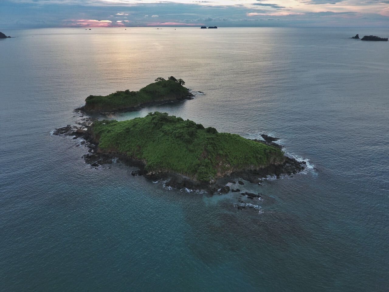 Vista aérea de dos pequeñas islas verdes rodeadas de mar tranquilo.