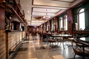 A restaurant with a bar area, multiple dining tables, and chairs. - Bremen Hotel (Harbin)