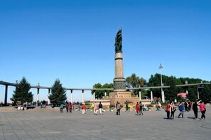 A public square with a central monument, open space, and trees. - Bremen Hotel (Harbin)