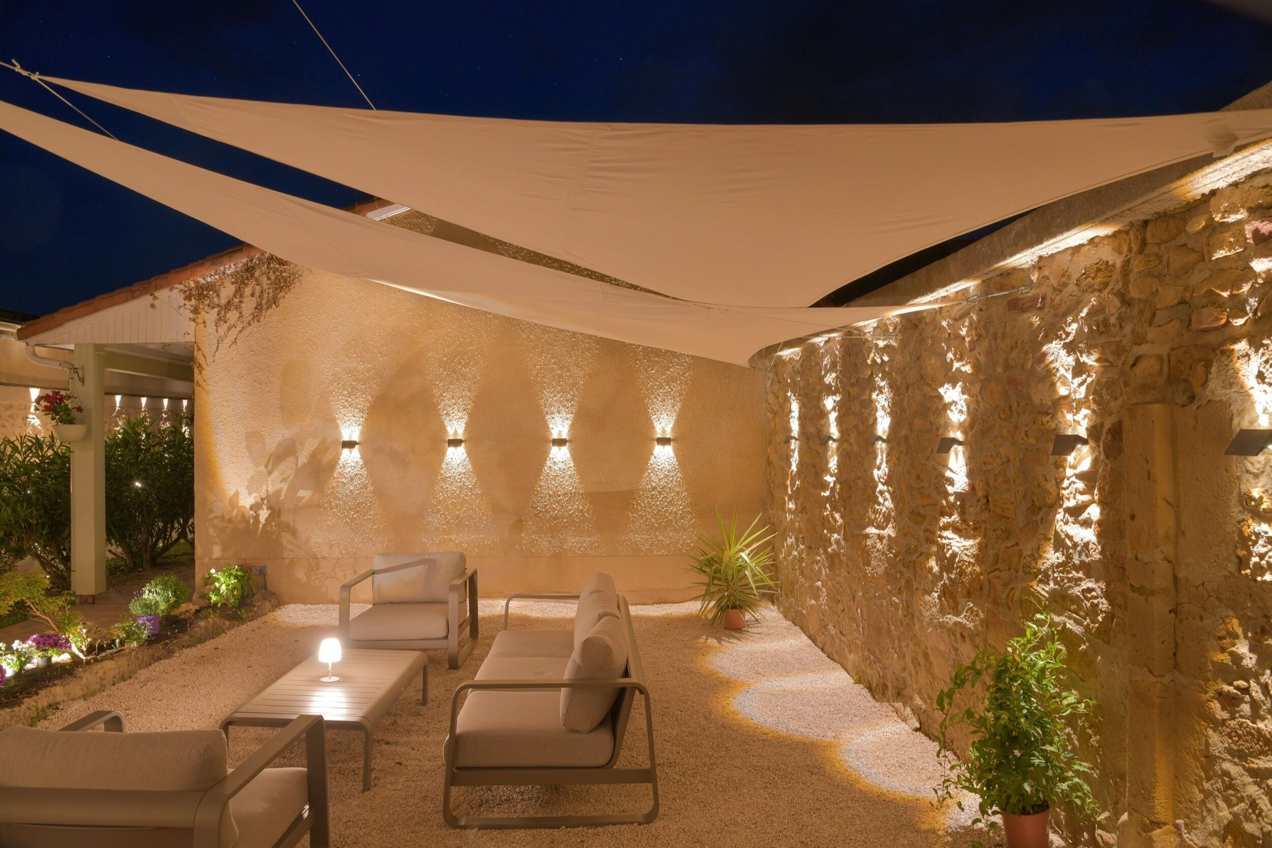 An outdoor patio with stone walls, a canopy, and seating.
