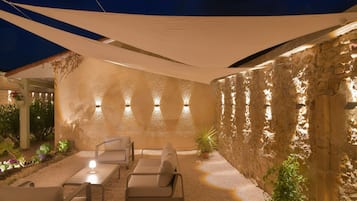An outdoor patio with stone walls, a canopy, and seating.