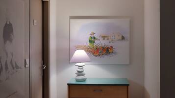 Un pasillo con una puerta, una lámpara de pared, una obra de arte enmarcada y un armario de madera.