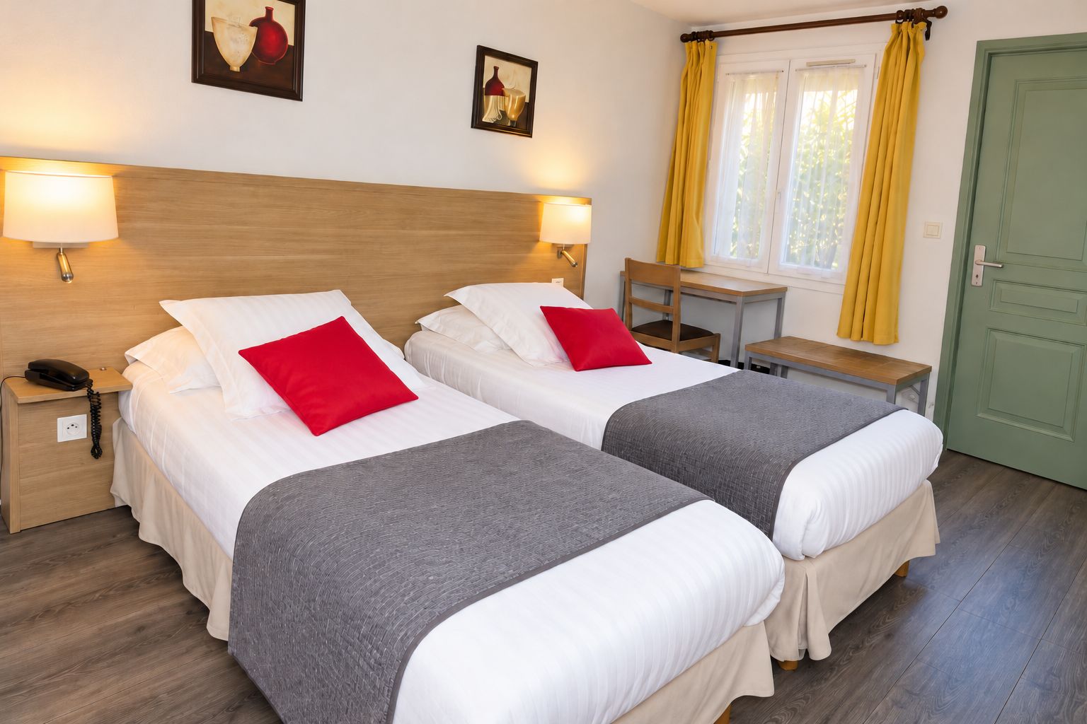 Habitación de hotel con dos camas, un escritorio, una silla y una puerta verde.