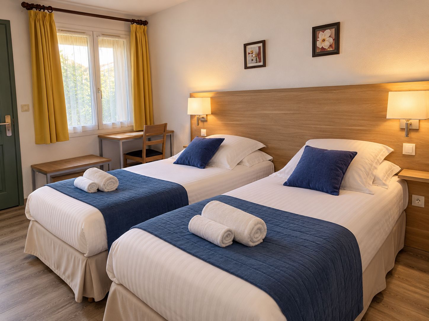Ein Hotelzimmer mit zwei Betten, einem Schreibtisch, einem Stuhl und einem Fenster mit Vorhängen.