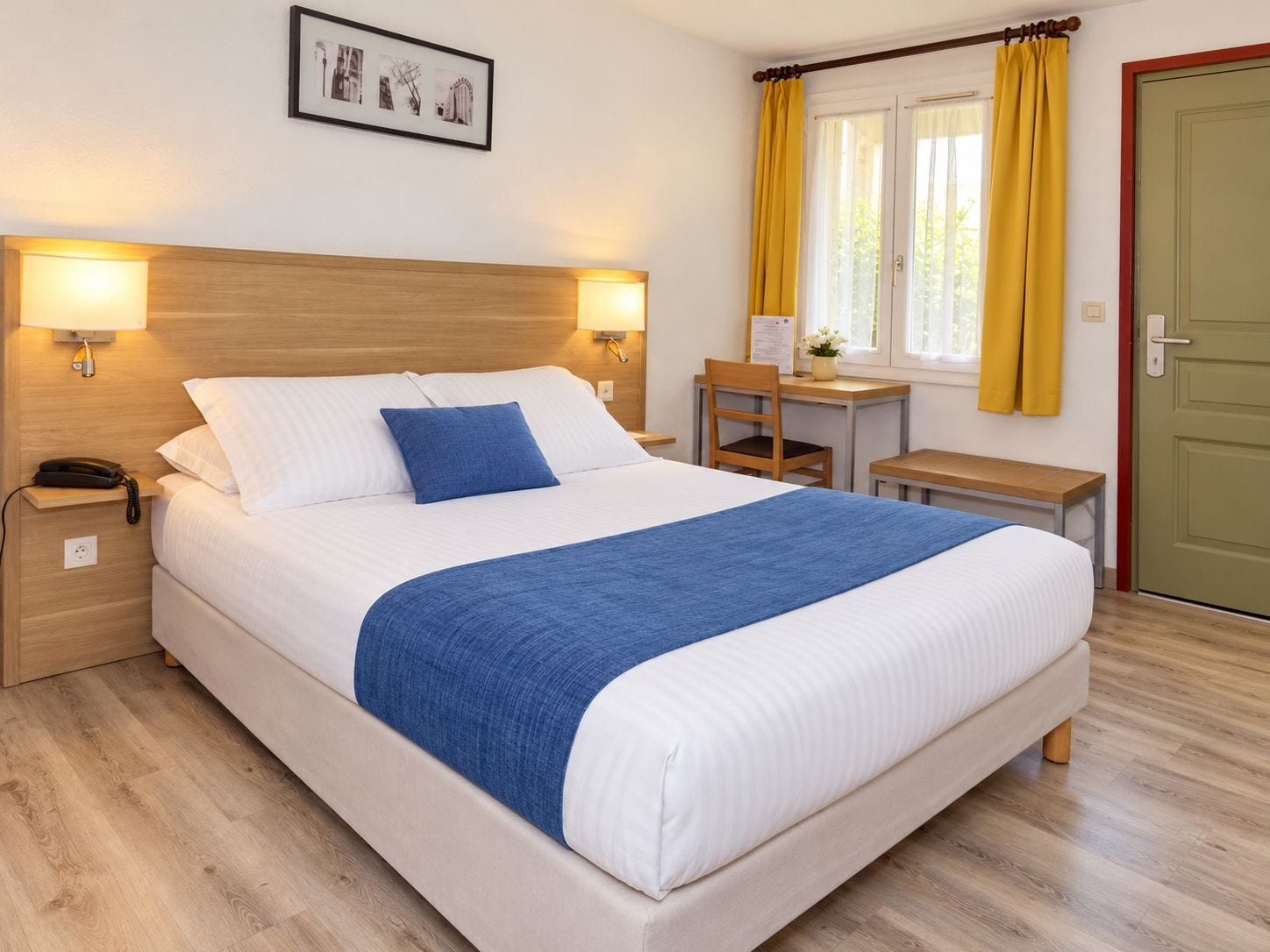 Une chambre d’hôtel avec un lit, des lampes de chevet, un bureau, une chaise, une petite table et une porte.