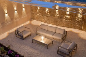An outdoor seating area with a stone wall, a sofa, two chairs, and a coffee table.