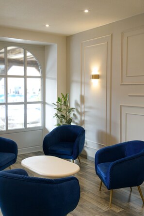A room with a large window, a plant, and blue upholstered chairs.