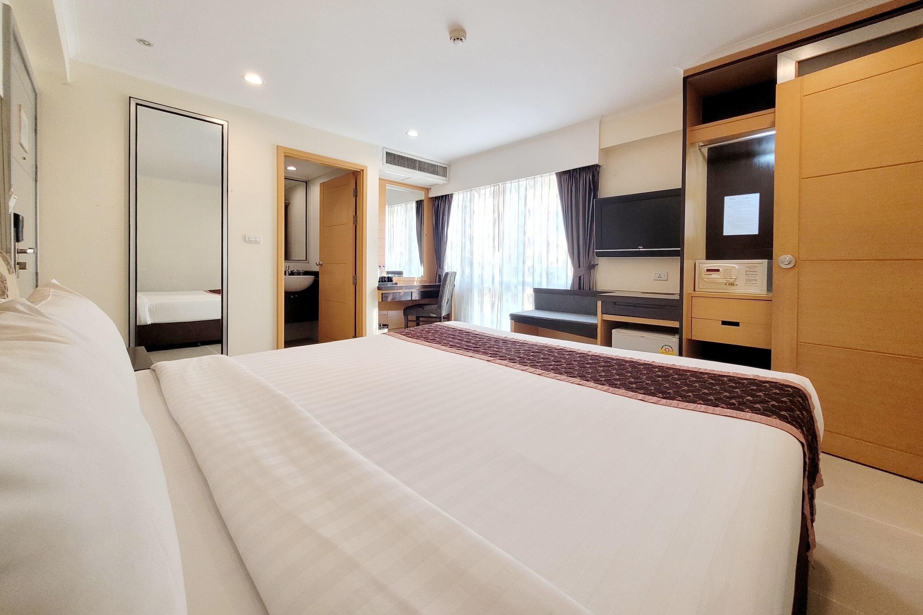 Una habitación de hotel con una cama grande, un escritorio, un televisor y un armario.