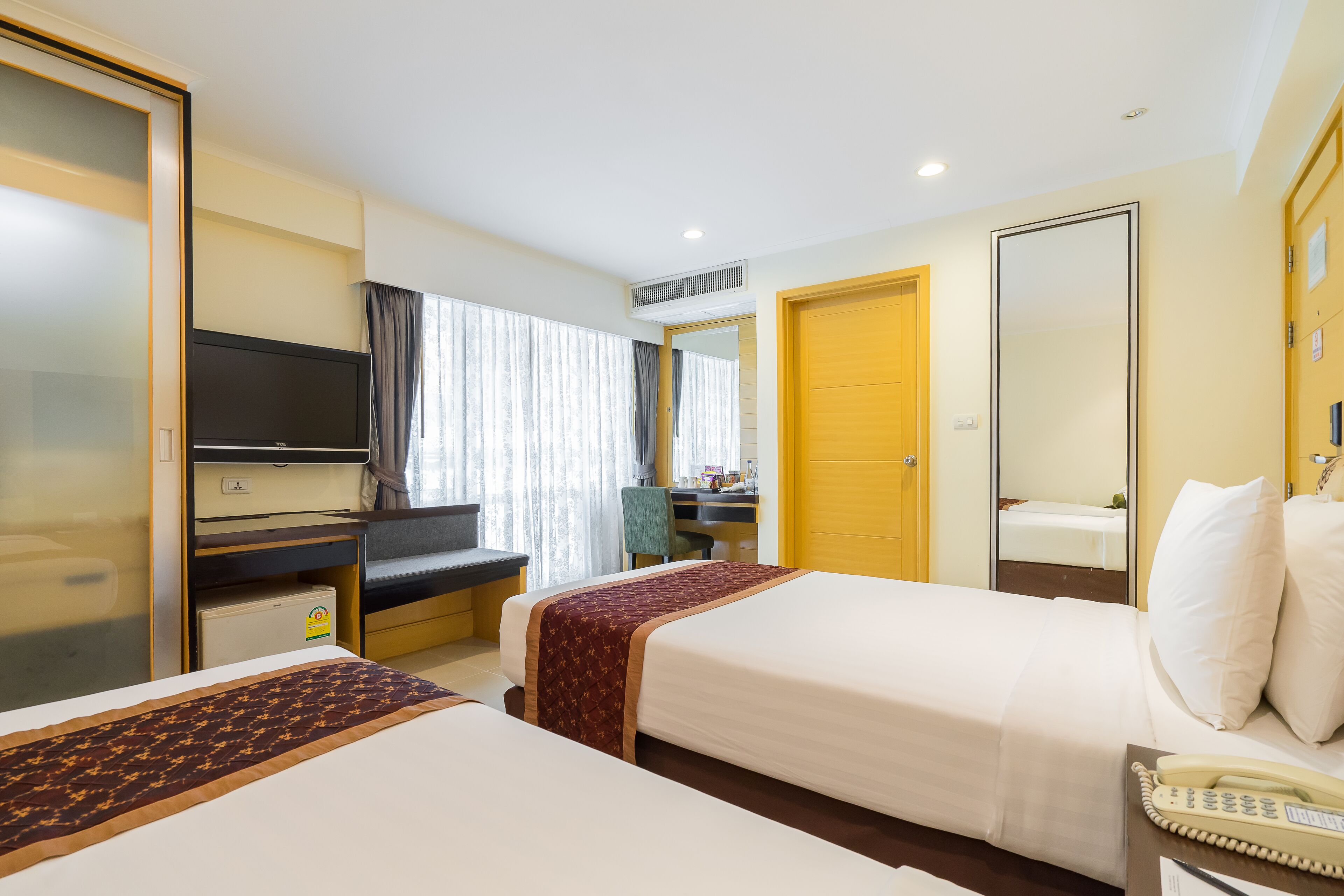 Une chambre d’hôtel avec deux lits, un bureau, une télévision et un miroir.