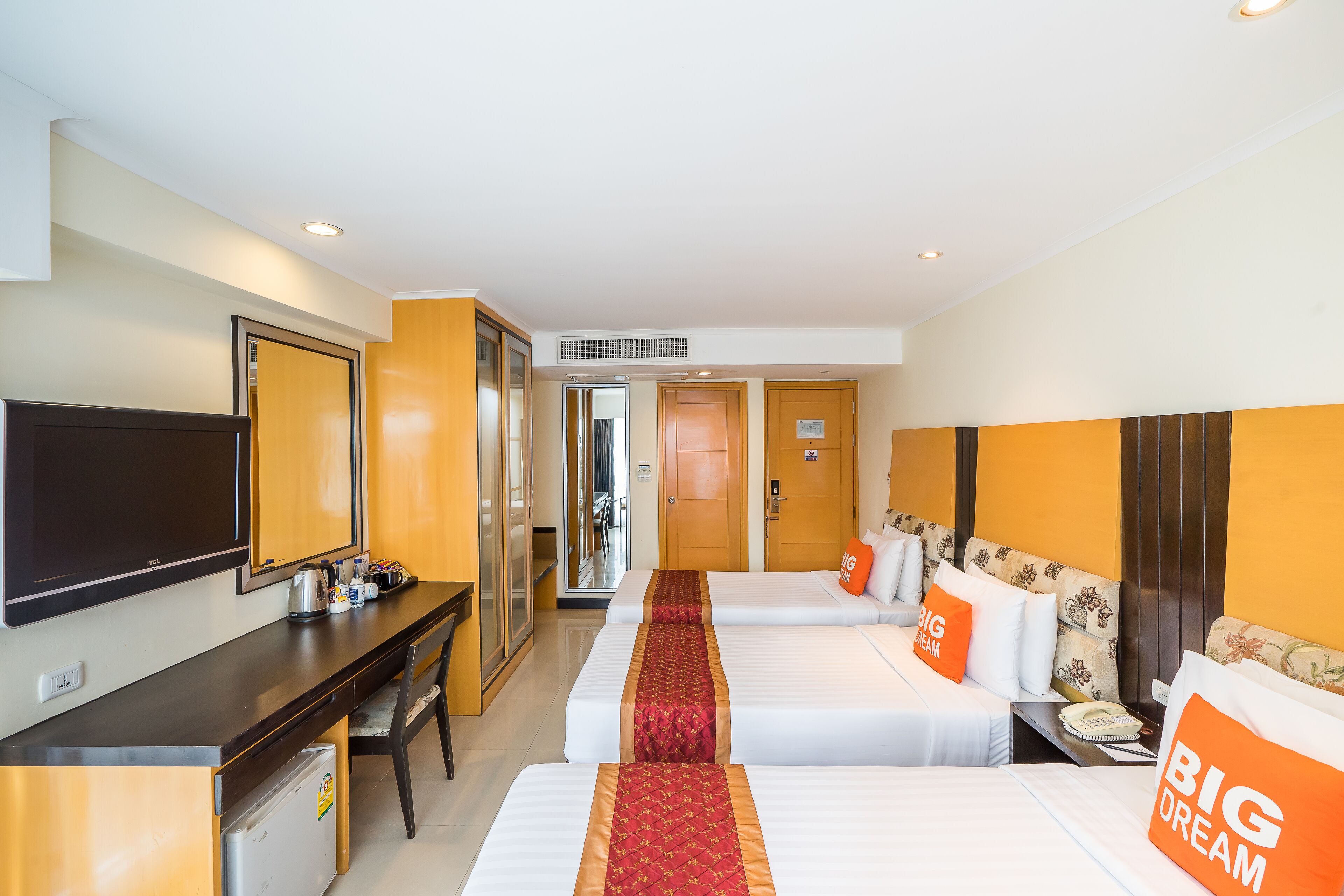Une chambre d’hôtel avec deux lits, un bureau, une télévision et un réfrigérateur.