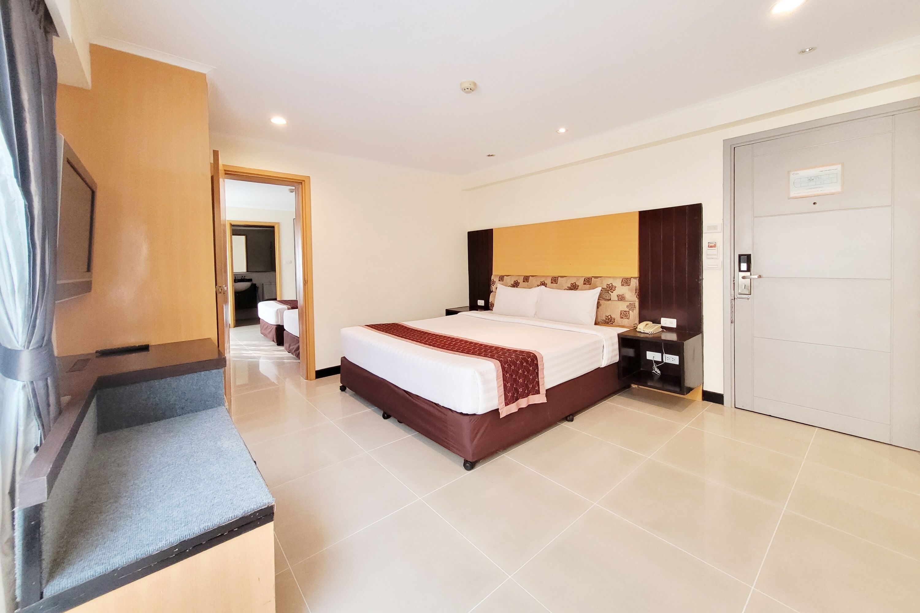 A hotel room with a bed, bedside tables, a TV, and a door.