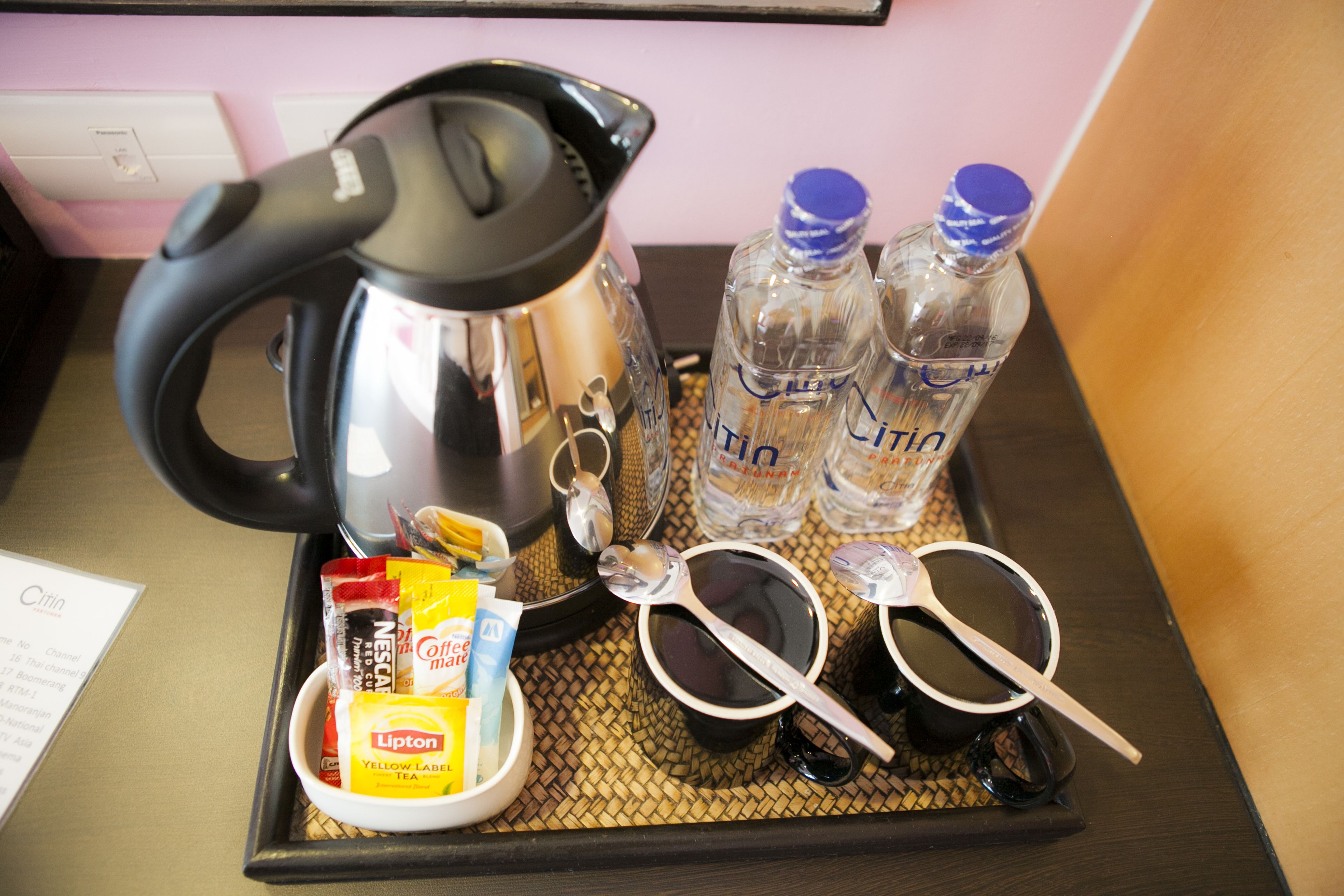 Un plateau avec une bouilloire, deux bouteilles d’eau, une tasse de thé, une paire de lunettes de soleil et quelques en-cas.