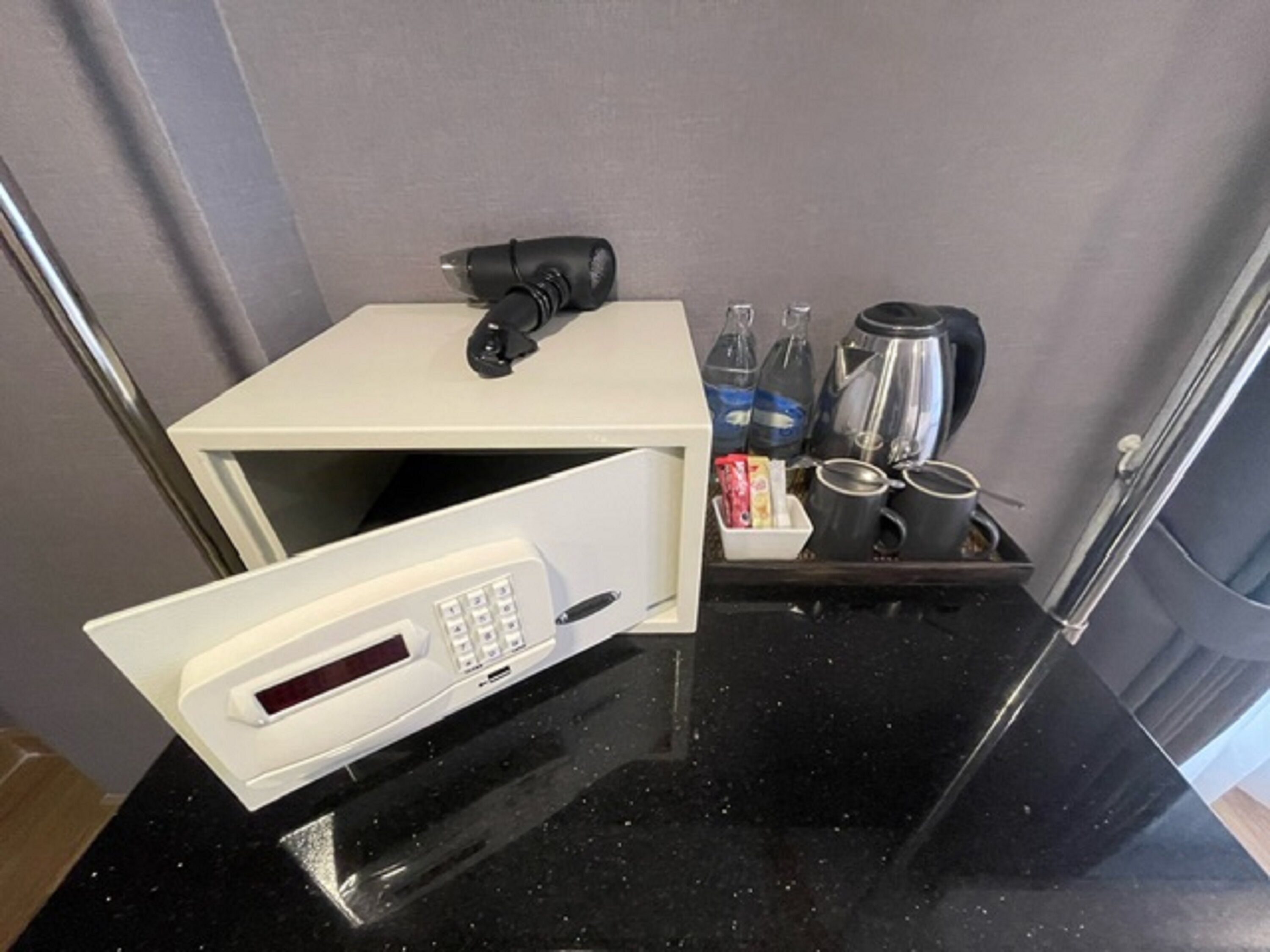Una kitchenette compacta con microondas, cafetera y espacio para guardar bebidas.
