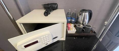 Una kitchenette compacta con microondas, cafetera y espacio para guardar bebidas.