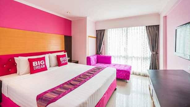A hotel room with a large bed, a pink sofa, and a TV on a stand. - Citin Pratunam Bangkok Hotel by Compass Hospitality (Bangkok)