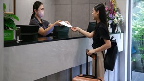 A reception desk with a receptionist and a guest. - Citin Pratunam Bangkok Hotel by Compass Hospitality (Bangkok)
