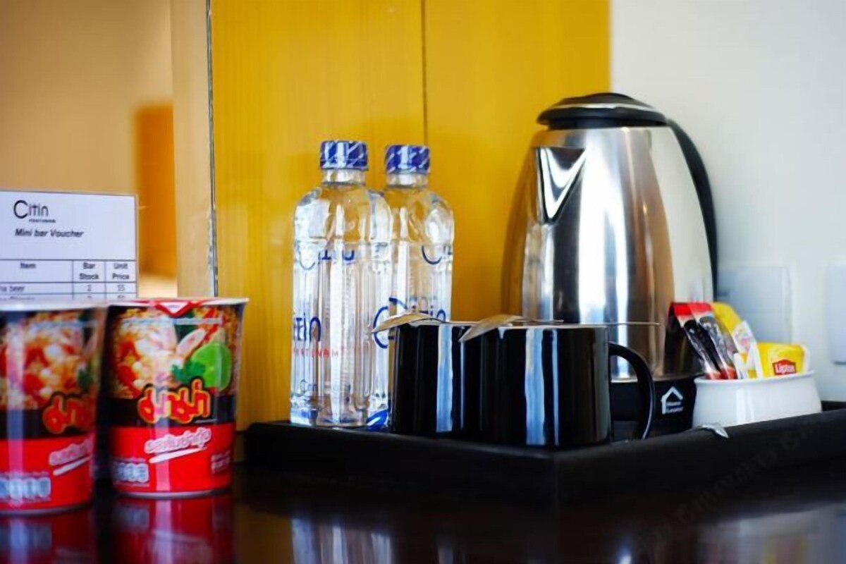 Uma bancada de cozinha com uma cafeteira, duas garrafas de água, um voucher do minibar e uma lata de comida.