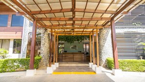 A covered outdoor area with a reception desk, stone walls, and a wooden pergola structure. - Nacazcol Hotel and Villas (Sardinal)
