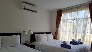 A hotel room with two beds, an air conditioner, a nightstand with a lamp, and a window with curtains. - Nacazcol Hotel and Villas (Sardinal)