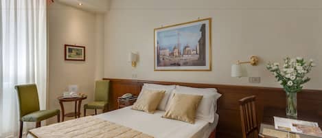 Habitación de hotel con una cama grande, un escritorio con silla, una mesita y una lámpara de pared.