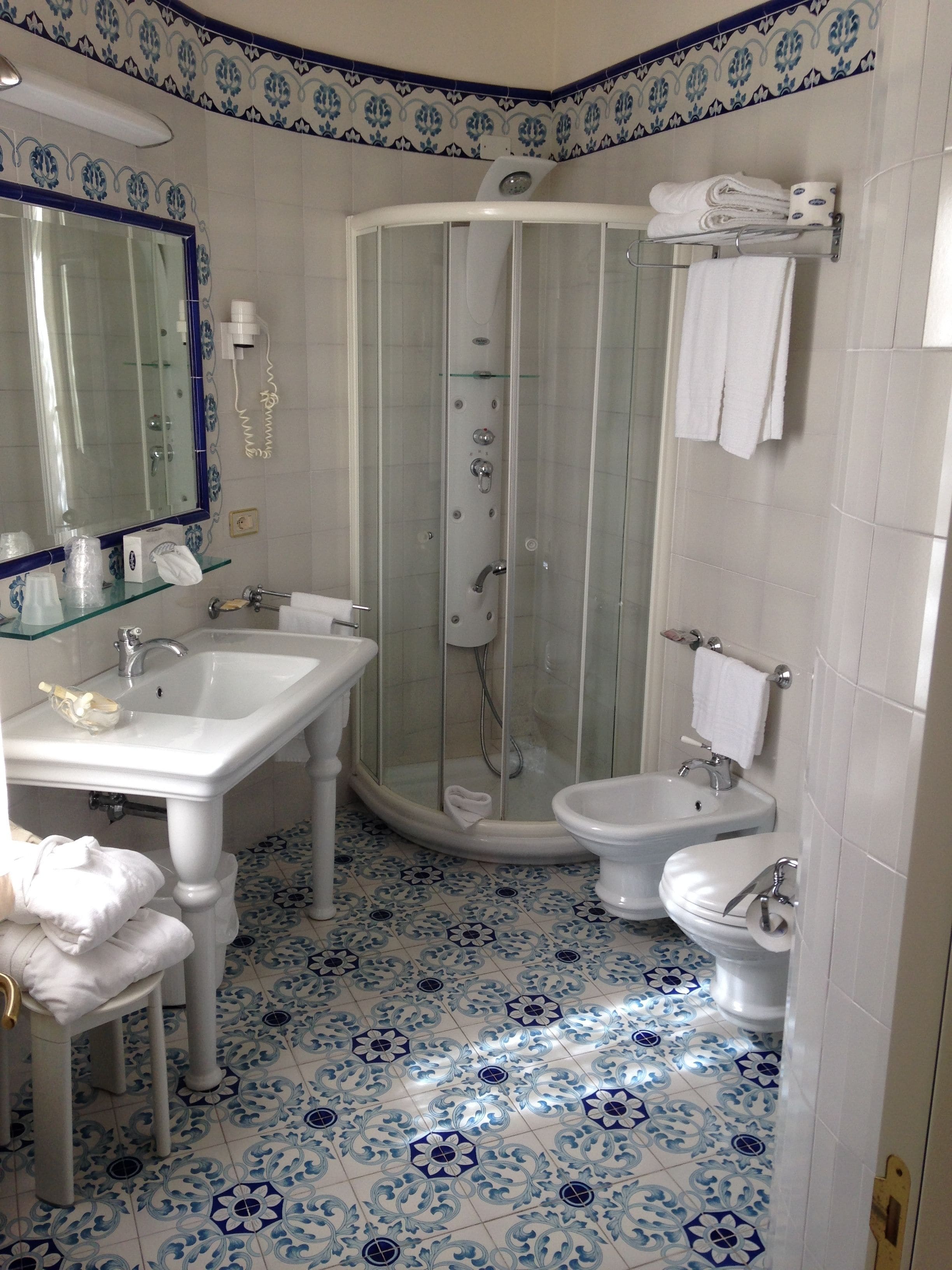 A bathroom with a shower, two sinks, a toilet, and a mirror.