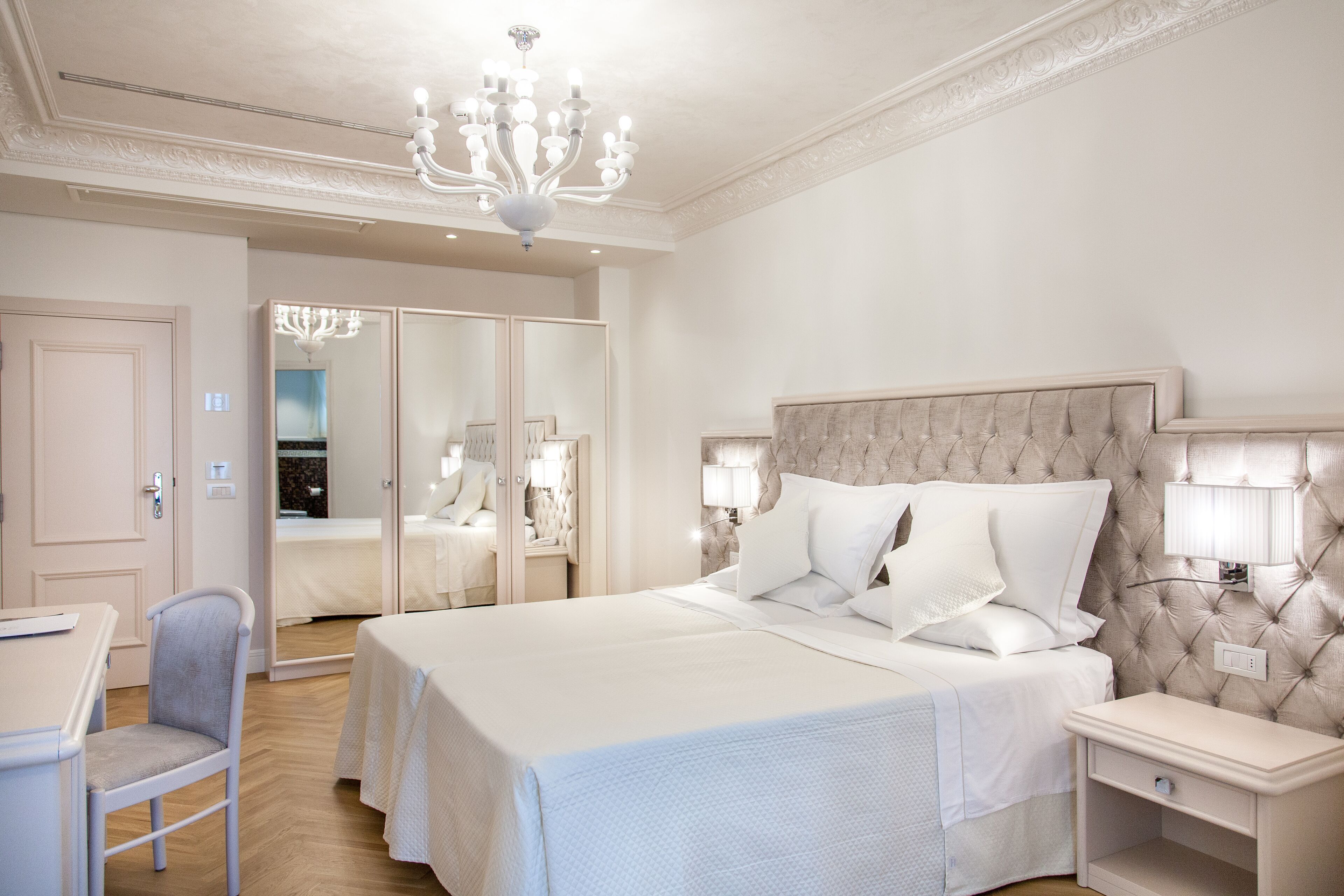Une chambre d’hôtel avec un grand lit, des lampes de chevet, une chaise et une armoire avec un miroir.