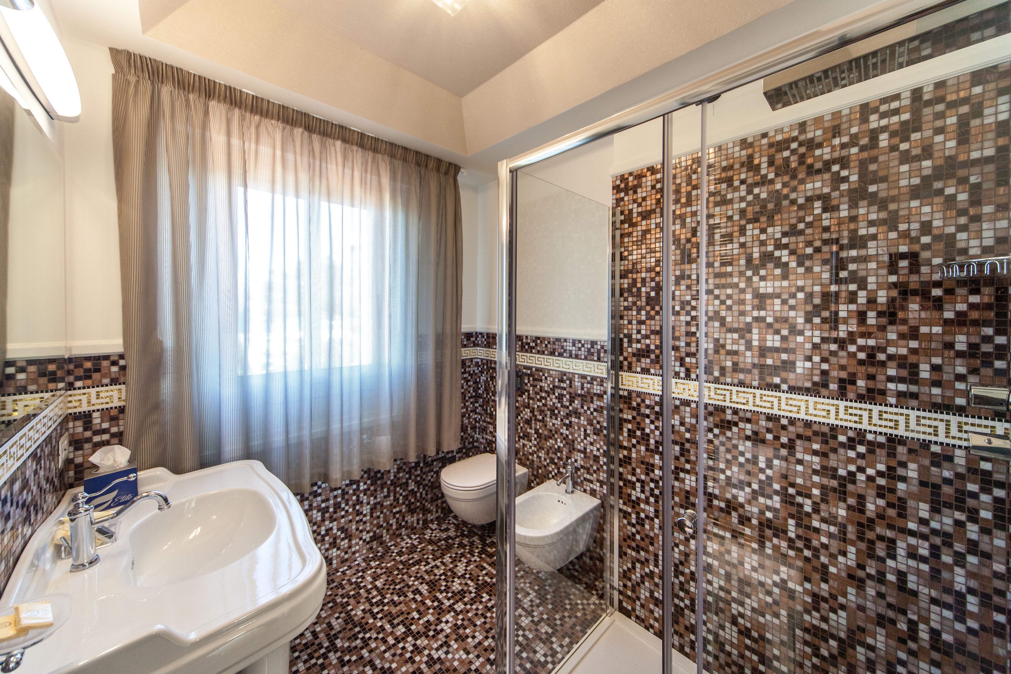 Un baño con lavamanos, inodoro y zona de ducha.