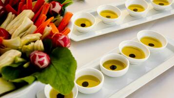 A white tray with small bowls of yellow liquid and a variety of sliced vegetables.