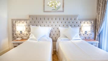 Hotellihuone, jossa on kaksi sänkyä, koristeltu pääty, yöpöytälamput, kehystetty kukka-aiheinen taideteos ja puinen yöpöytä.